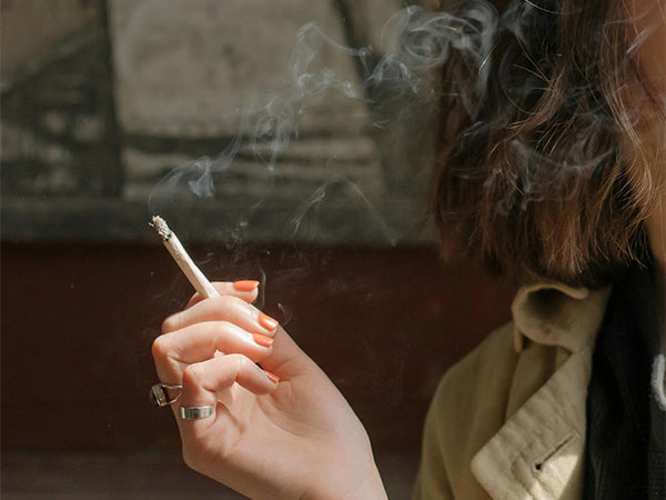  a woman holds a lit cannabis joint – SMOKEA 